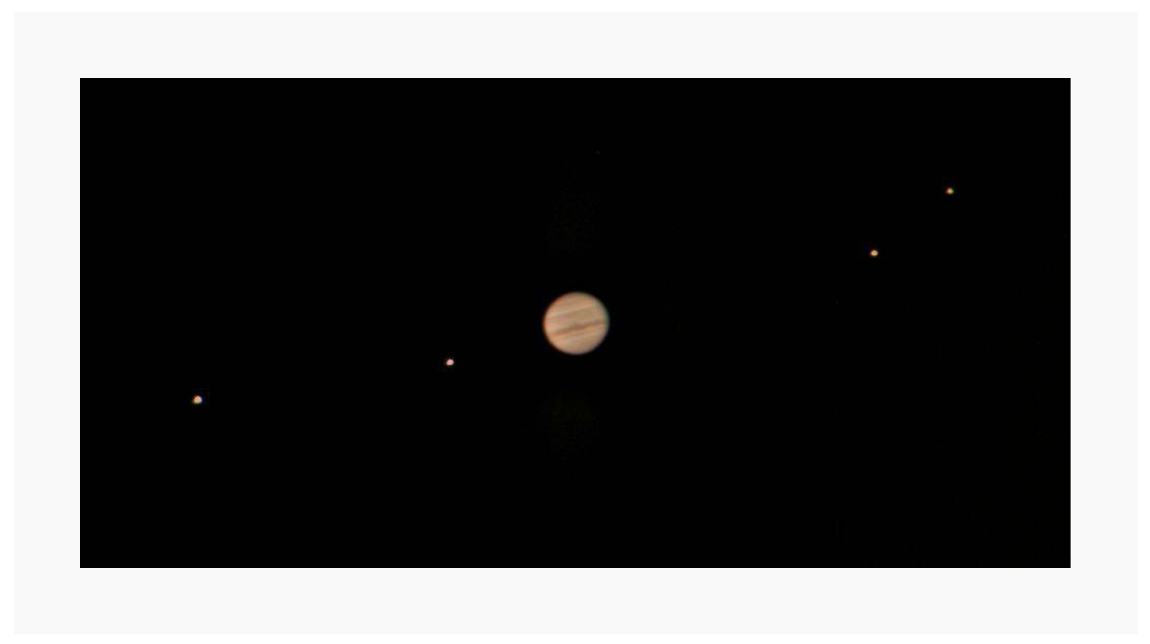 A photo of the moons (small dots) orbiting the planet Jupiter.